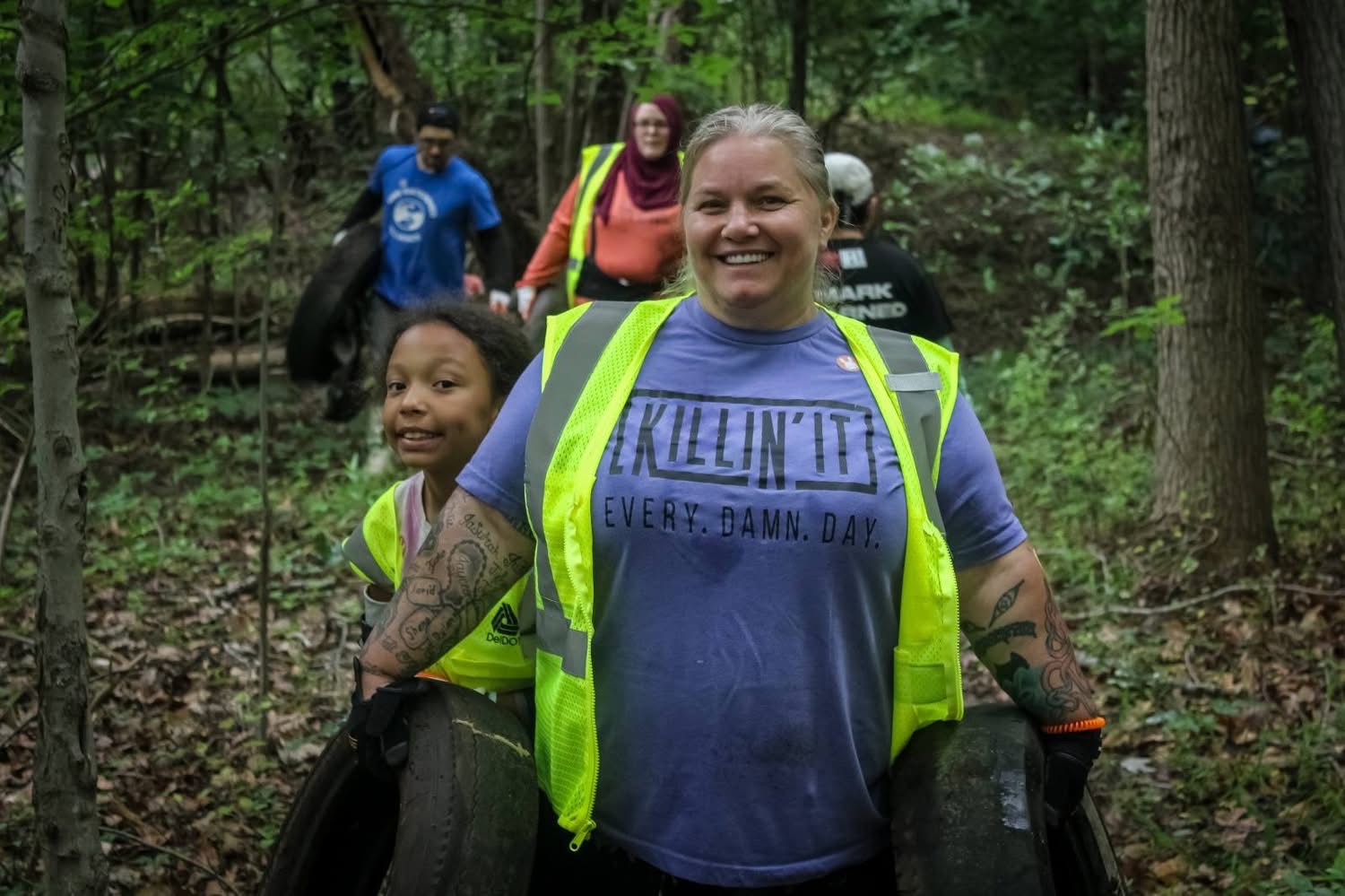 Claymont residents carrying tires out of the woods during a community cleanup
